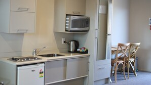 A compact kitchenette with a microwave, sink, and small refrigerator. - Albert Court Motor Lodge (Hamilton)