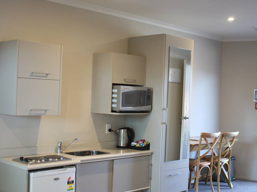 Una kitchenette compacta equipada con microondas, pileta y heladera pequeña.