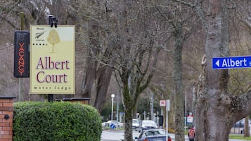 A sign for Albert Court Motor Lodge with a tree and a star rating.