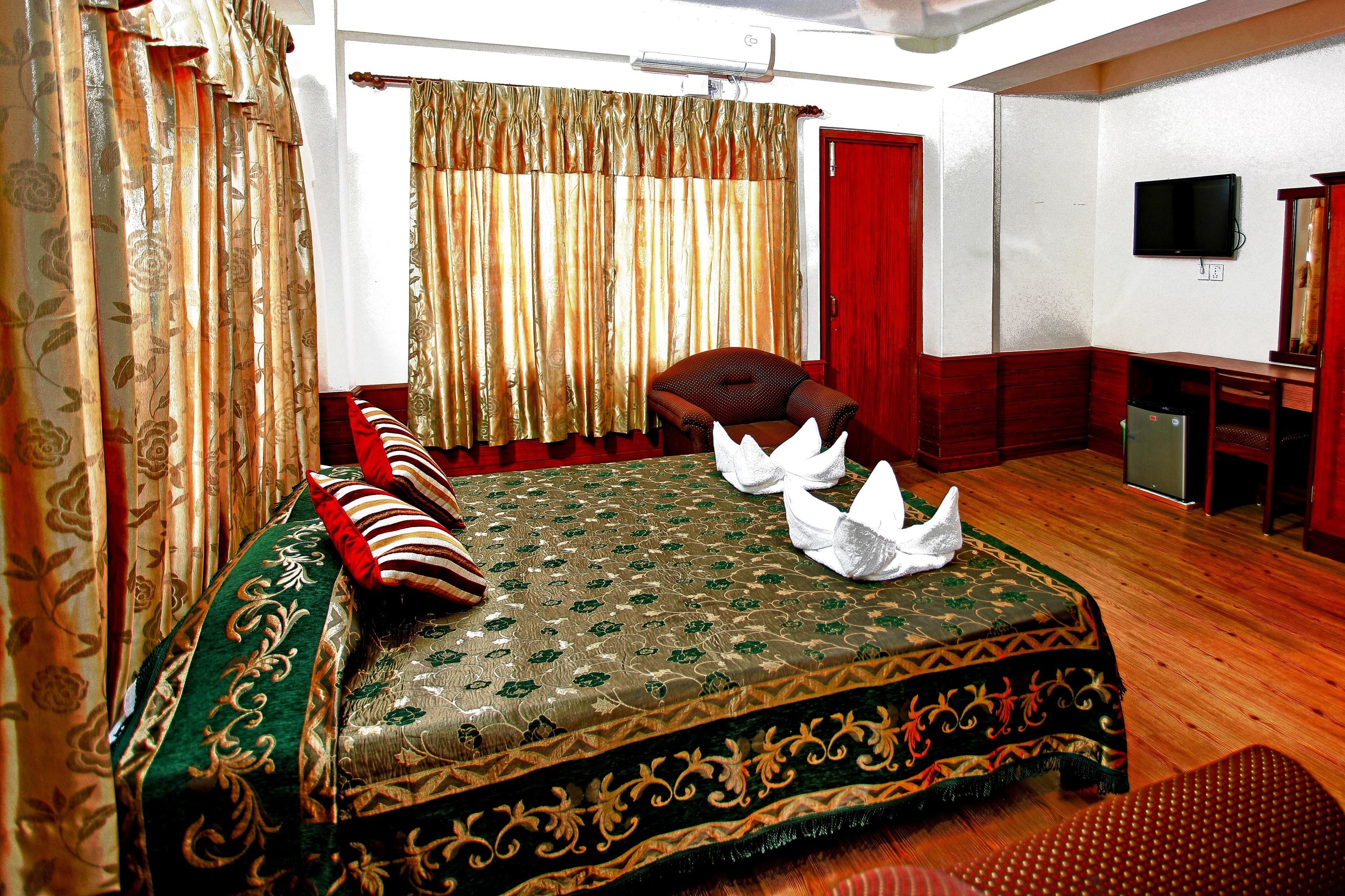 Un dormitorio ordenado con una cama, una silla, un televisor y un escritorio.