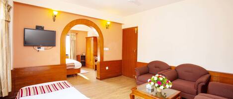 A hotel room with a bed, a sofa, a coffee table, a TV, and a ceiling fan.