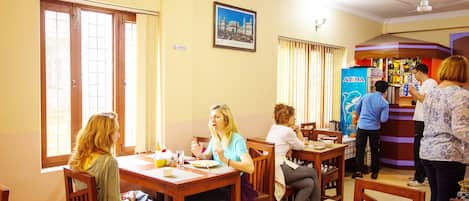 Un restaurante con mobiliario de madera, una zona de bar y un cuadro en la pared.