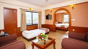 Una habitación de hotel con cama, sofá, televisión y ventana con cortinas.