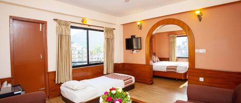 A hotel room with a bed, a sofa, a TV, and a window with curtains.