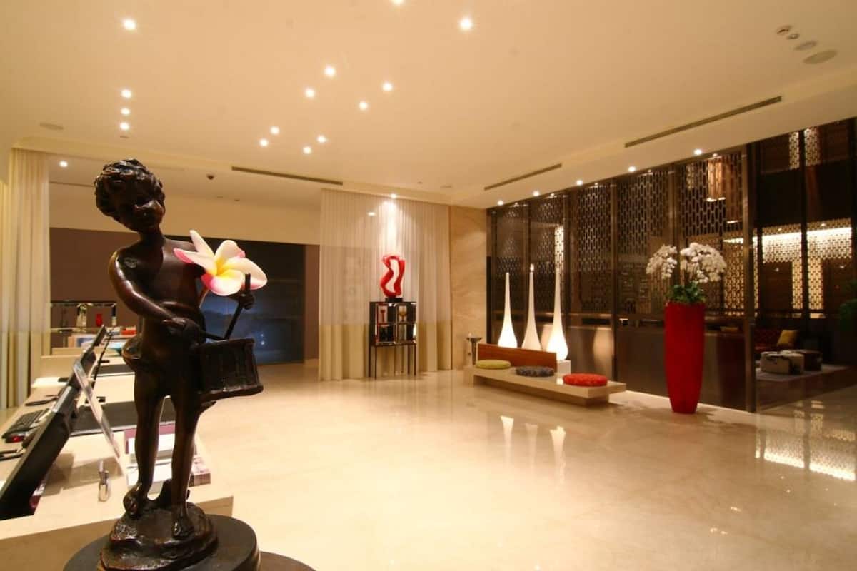 Un vestíbulo moderno con una estatua, una recepción y un área de estar con un jarrón grande de flores.