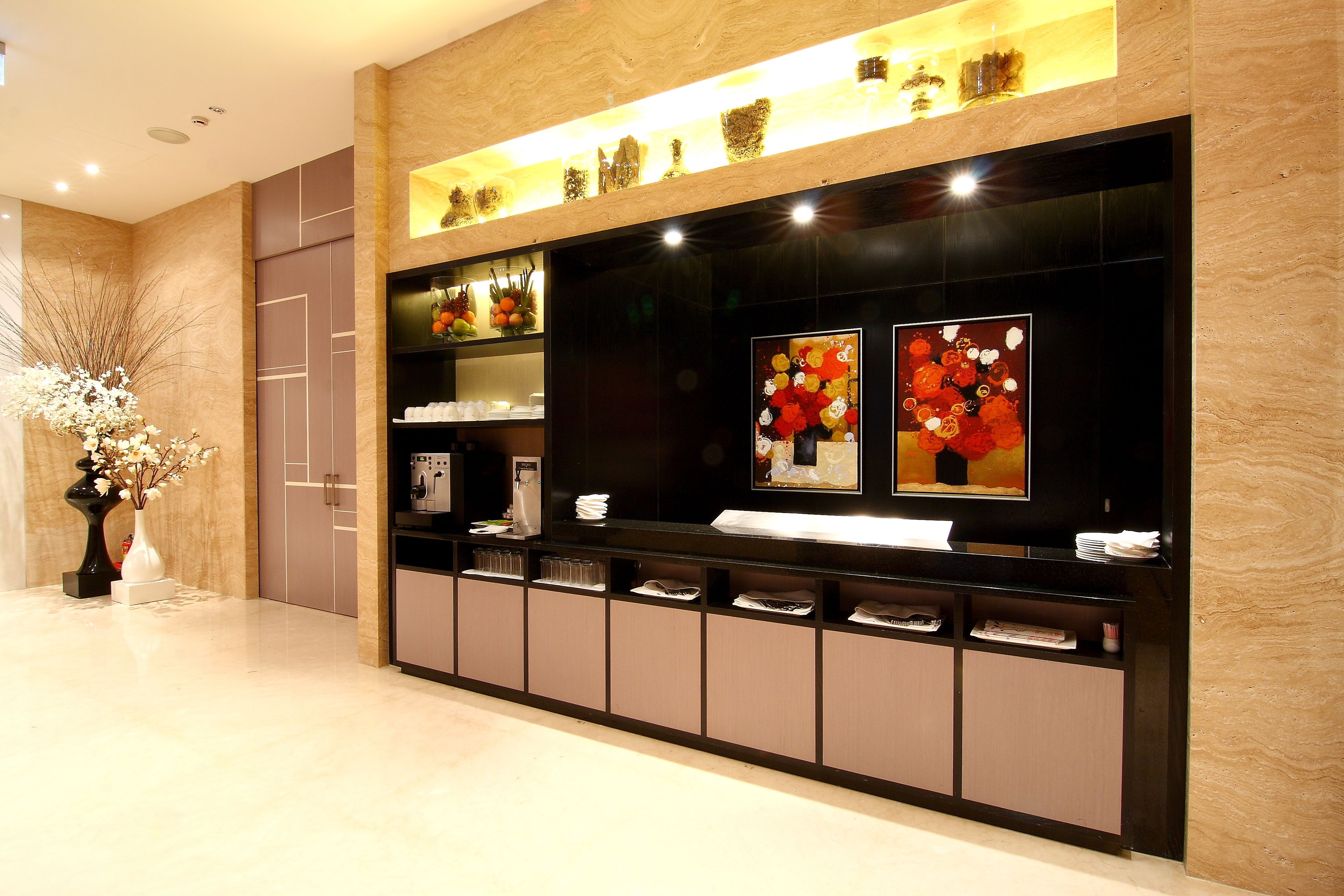 A reception desk with a modern design, featuring a black and beige color scheme, a glass display case with decorative items, and a wall-mounted television.