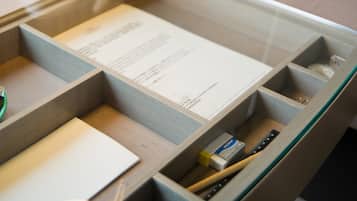 A wooden desk with compartments containing a menu, a ruler, and a small box labeled 'YONI'.
