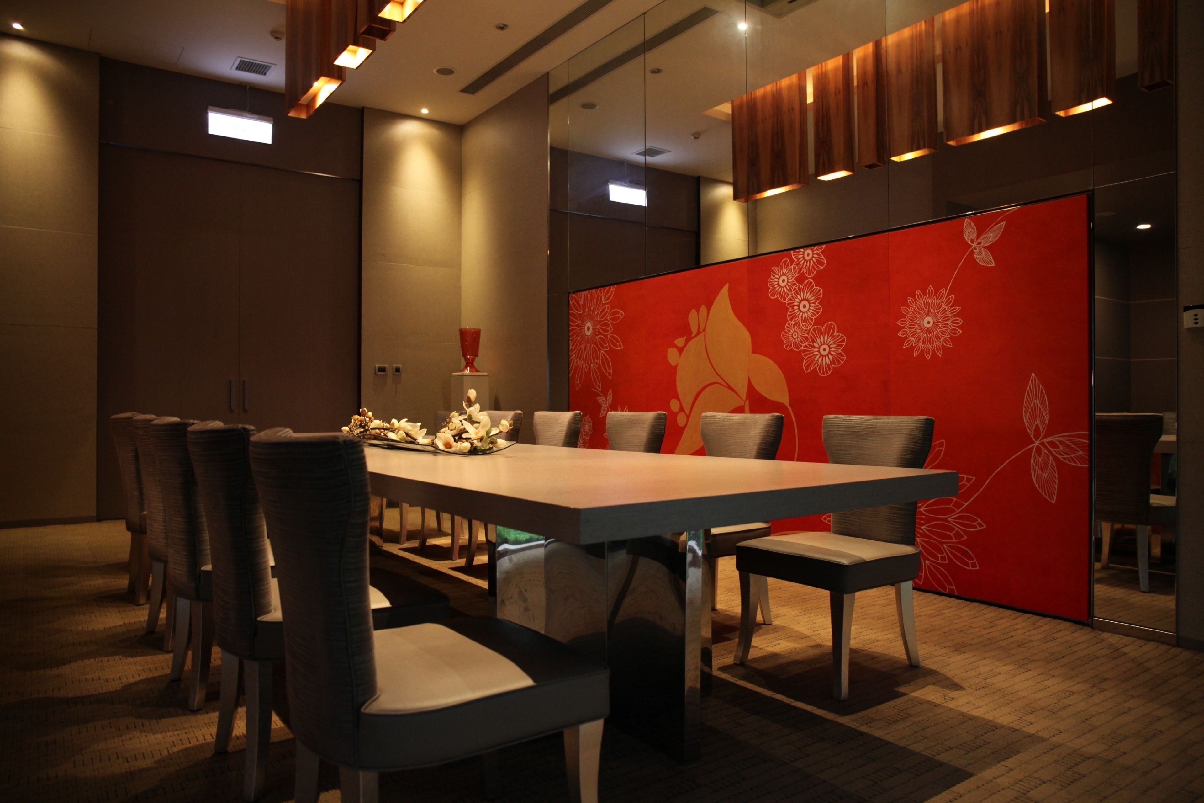 A conference room with a long table, several chairs, and a red decorative partition.