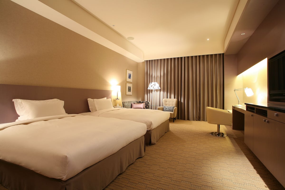 Una habitación de hotel con dos camas, un escritorio, una silla y un televisor.