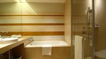 Un baño moderno con ducha de vidrio, una bañera independiente y un tocador con lavamanos y espejo.