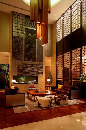A lobby with a large wall mural, seating area, and a water feature. - Hung's Mansion (Taichung)