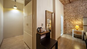 A hotel room with a wooden floor, a dark wooden desk, a mirror, a bedside table with a lamp, and a brick wall. - Nine Istanbul Hotel (Istanbul)
