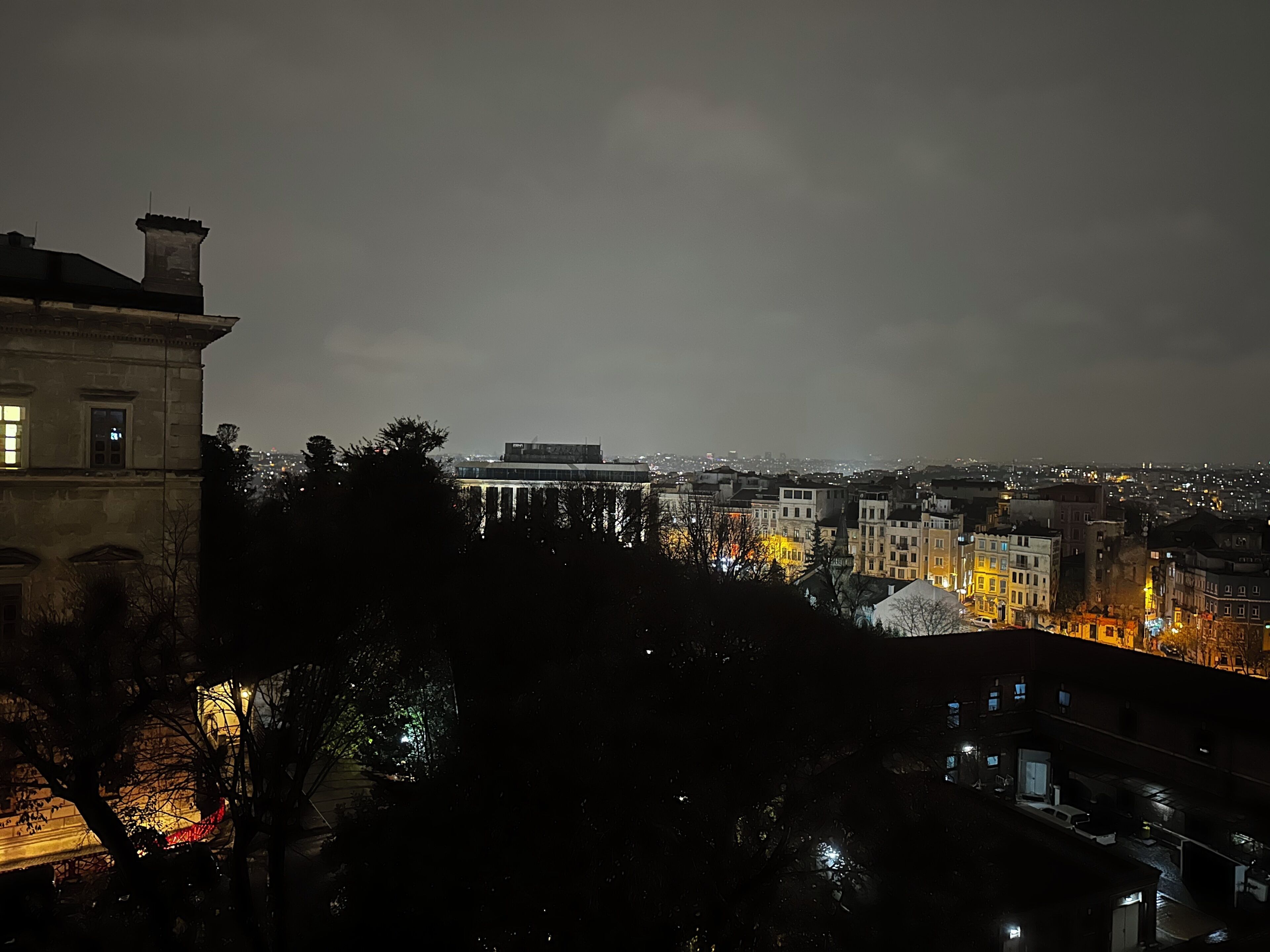 A nighttime cityscape with buildings and a bridge.