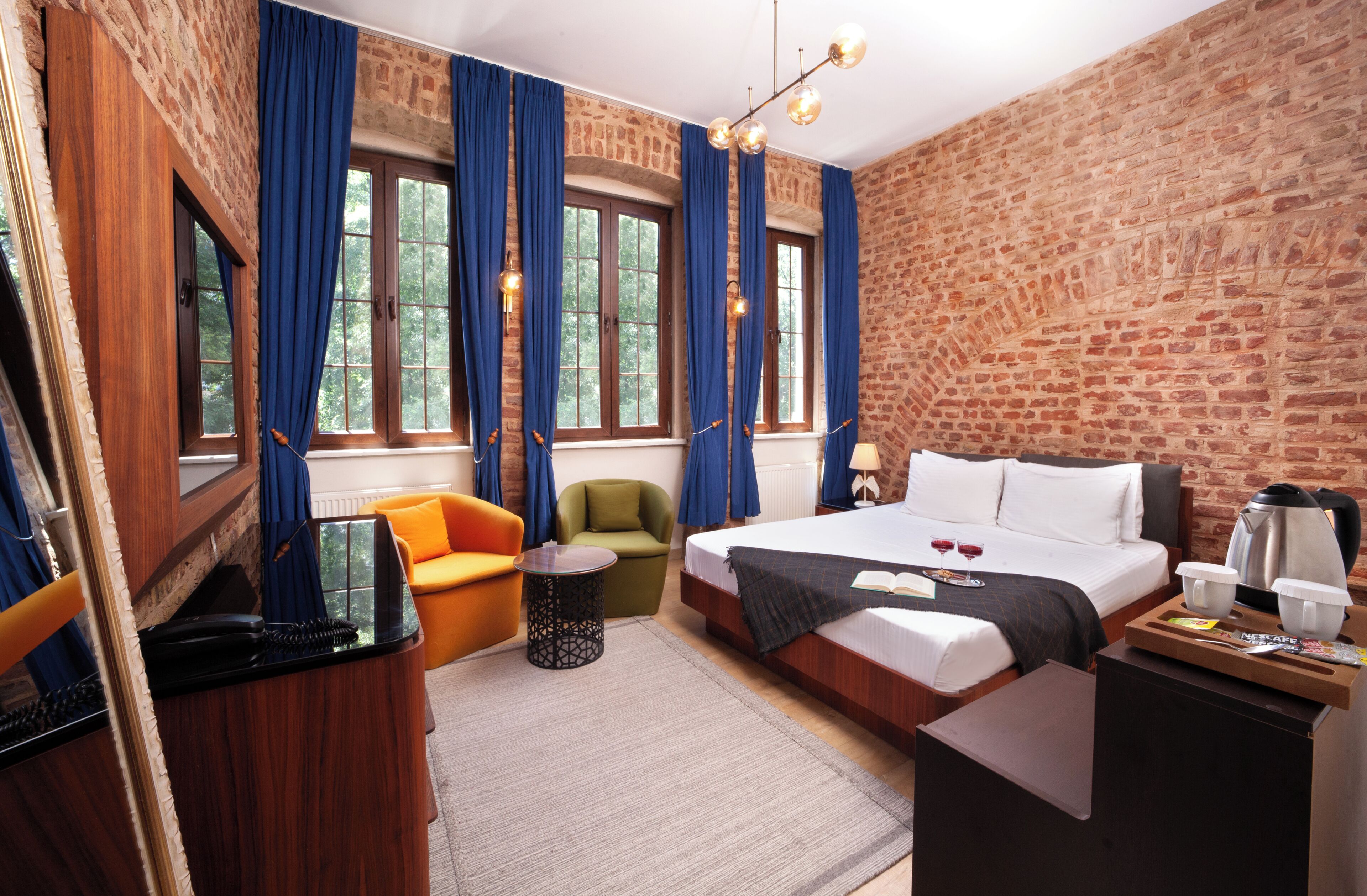 Ein Hotelzimmer mit Backsteinwand, einem Bett, einem Schreibtisch, einem Sessel und einem Sofa.