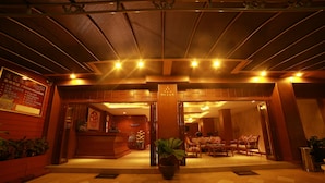A hotel lobby with a reception desk, seating area, and a large potted plant. - Lotus Hotel Patong (Patong)