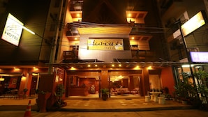 A hotel entrance with a signboard, outdoor seating area, and potted plants. - Lotus Hotel Patong (Patong)