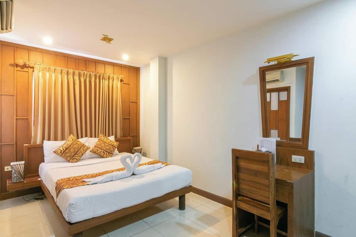 A hotel room with a wooden bed, a wooden desk, and a mirror.