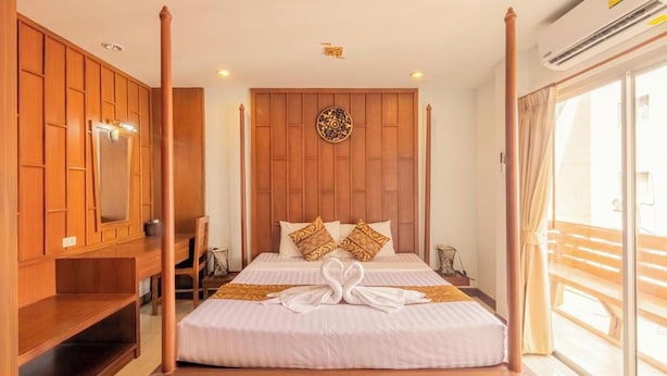 A four-poster bed with a wooden headboard, a large mirror, and a decorative wall piece. - Lotus Hotel Patong (Patong)