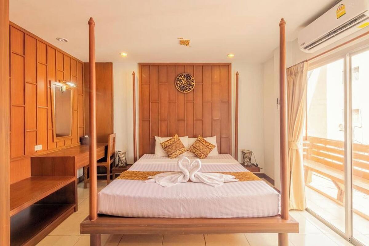 A four-poster bed with a wooden headboard, a large mirror, and a decorative wall piece.