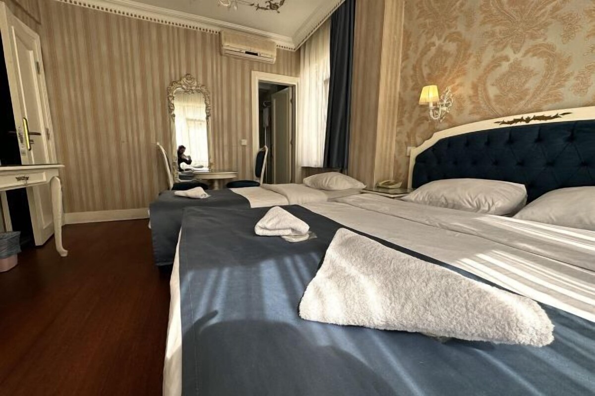 Une chambre d’hôtel avec deux lits, un bureau et un miroir.