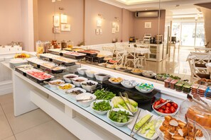 A buffet with various food items and a seating area with white chairs and tables. - Mr. Bird Hotel (Istanbul)