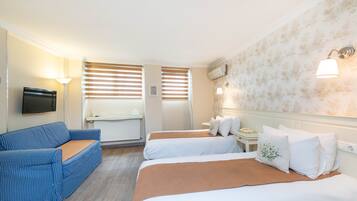 Habitación de hotel con dos camas, un sofá, un televisor y una ventana con persianas.