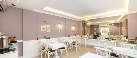 Uma sala de jantar moderna com mobiliário branco e uma ilha central com apresentações de comida.