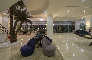 Um hall amplo com palmeira, área de estar e lustre.