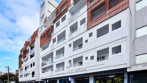 Ett hotell med flera våningar och en modern fasad, med balkonger som har räcken av trä och en skylt som visar att det är ett hotell.