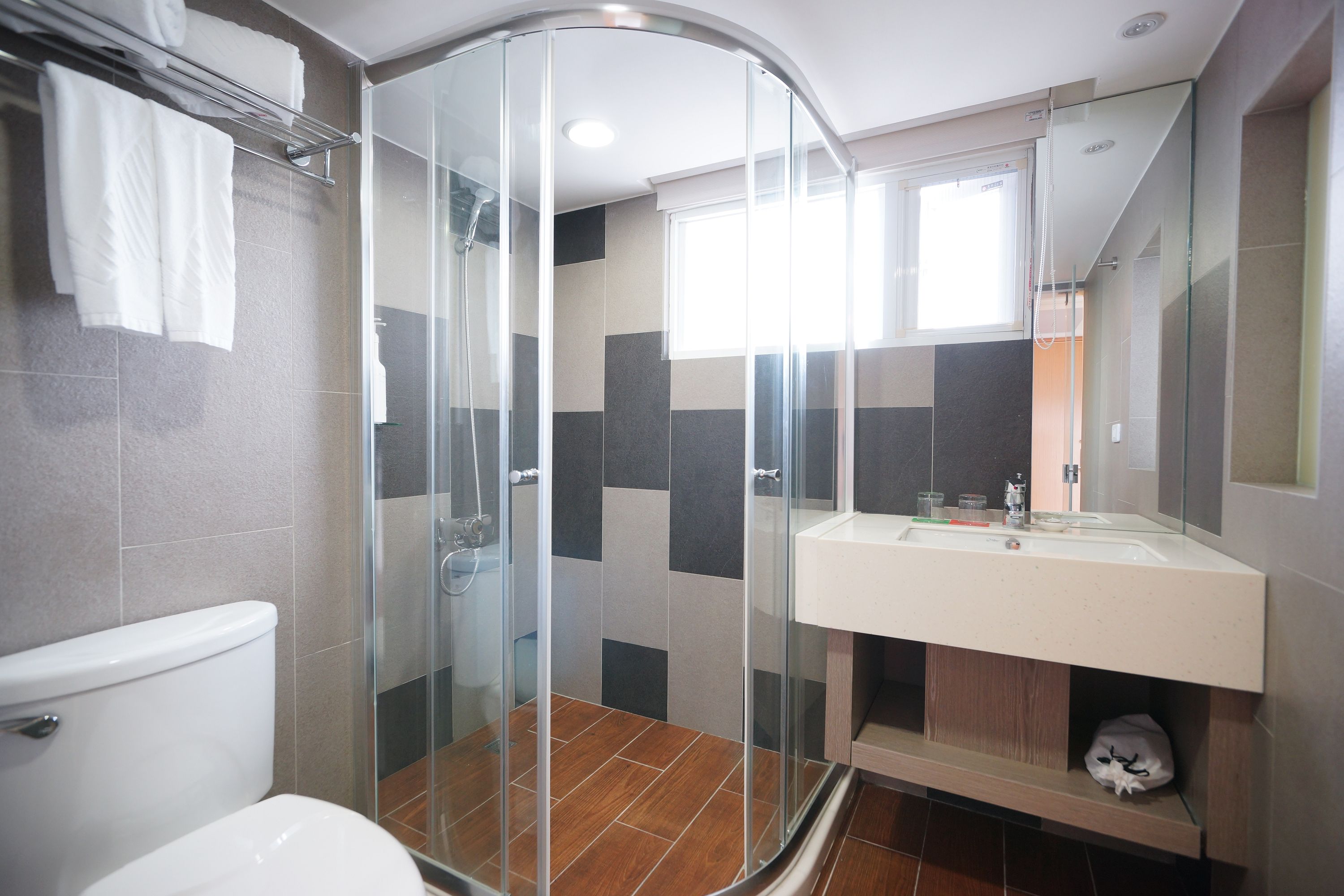A modern bathroom with a glass shower enclosure, a white sink, and a toilet.