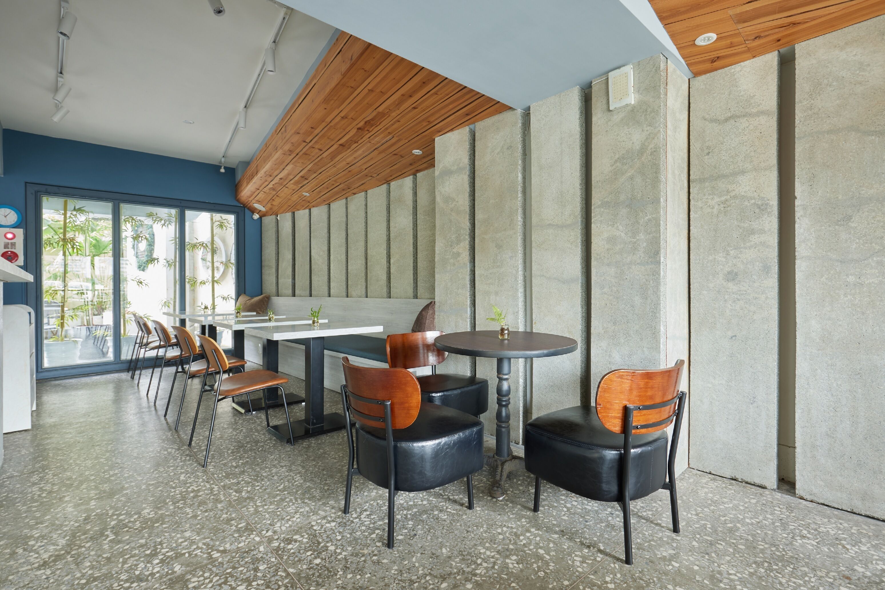 A modern interior with a long counter, several chairs, and a large window with a view of greenery.