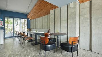A modern interior with a long counter, several chairs, and a large window with a view of greenery.