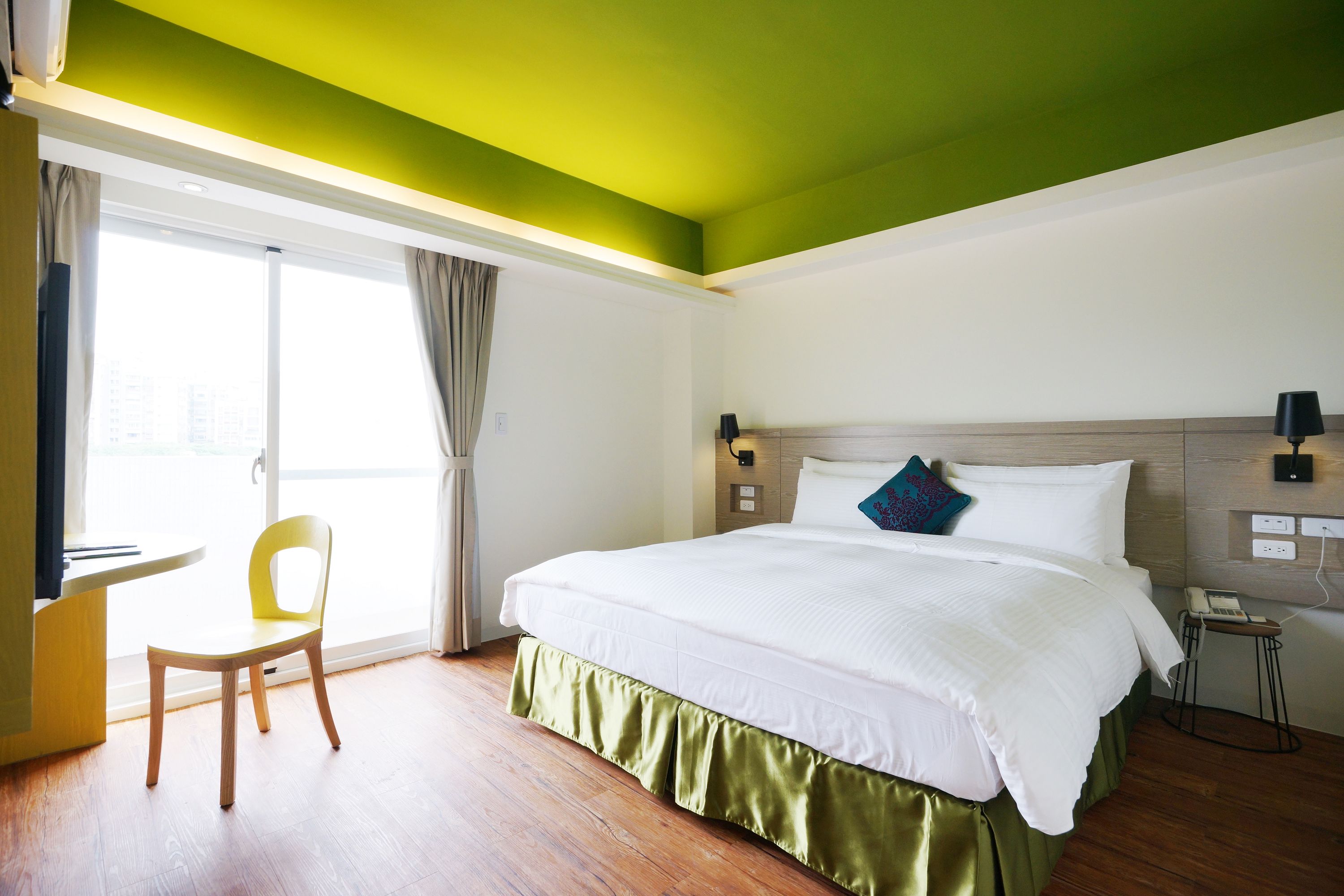 A hotel room with a large bed, a desk, and a chair.