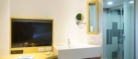 Un baño moderno con televisión, lavamanos y ducha.