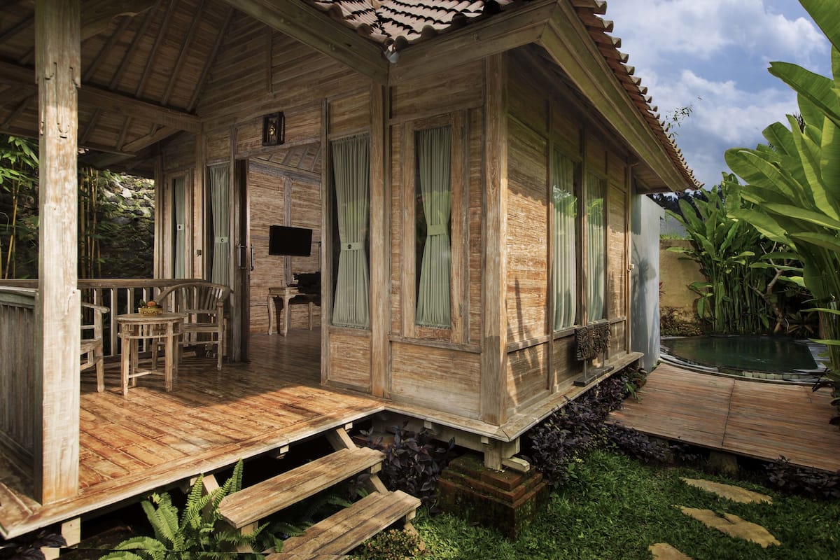 Ein Holzhaus mit Veranda, Pool und Essbereich.
