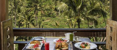 A wooden table set for breakfast with a view of a lush, green landscape.