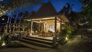 A traditional building with a tiled roof, a covered patio with seating, and a stone staircase leading up to it. - Pondok Sebatu Villa (Sebatu)