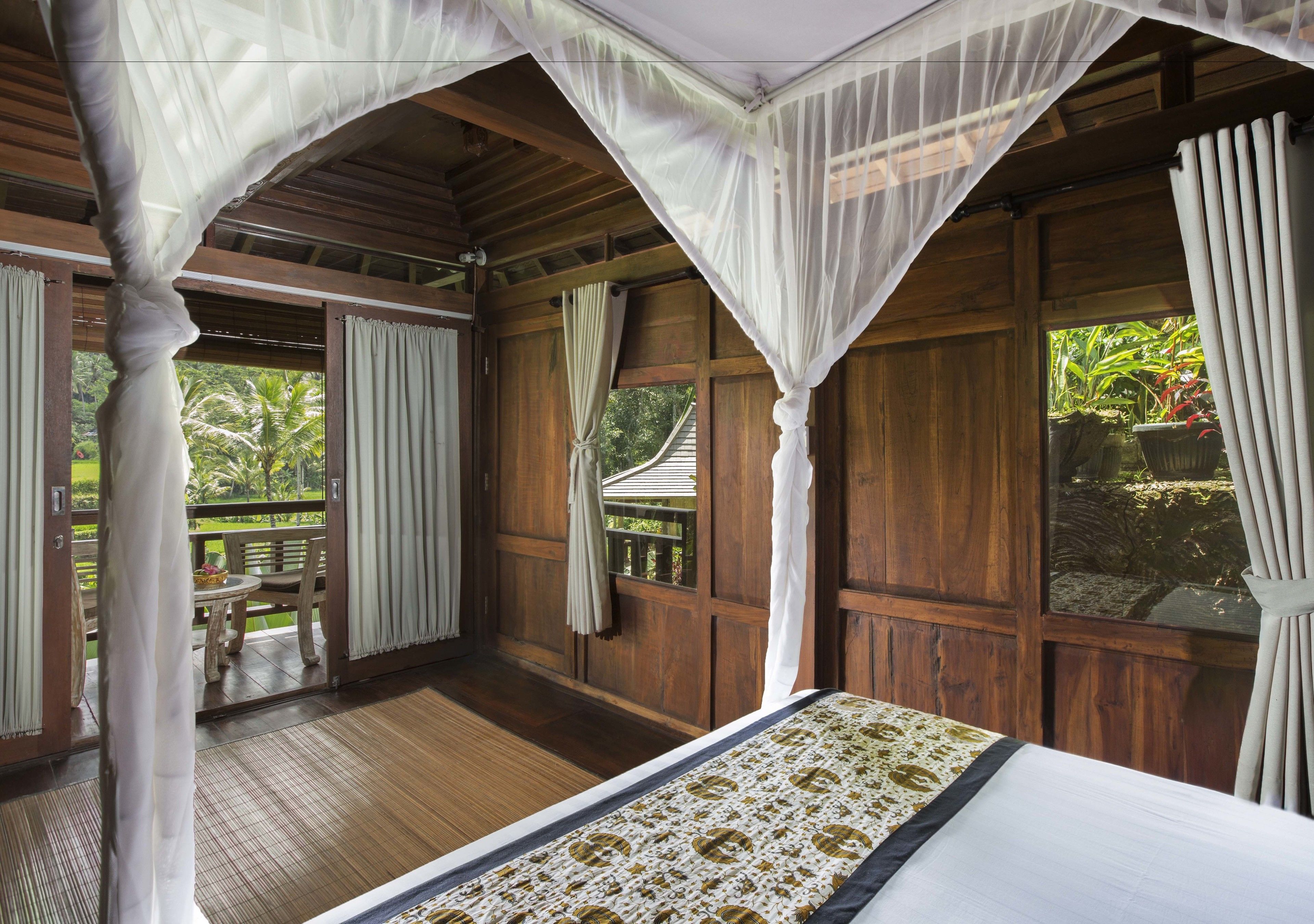 A room with a bed, wooden walls, and a balcony with a table and chairs.