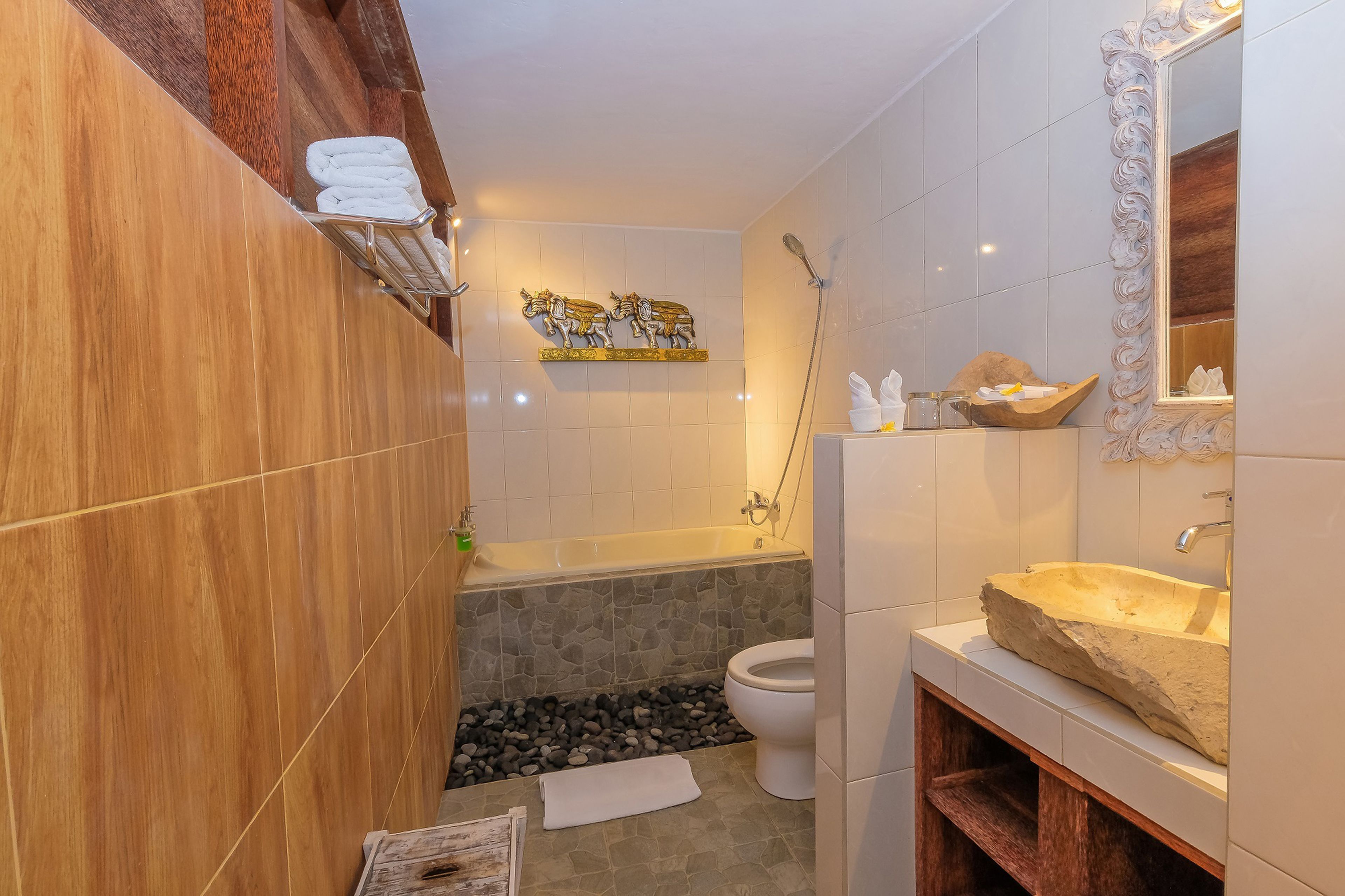 A bathroom with a bathtub, a sink, and a toilet. There is a towel rack with towels and a decorative wall piece above the bathtub.