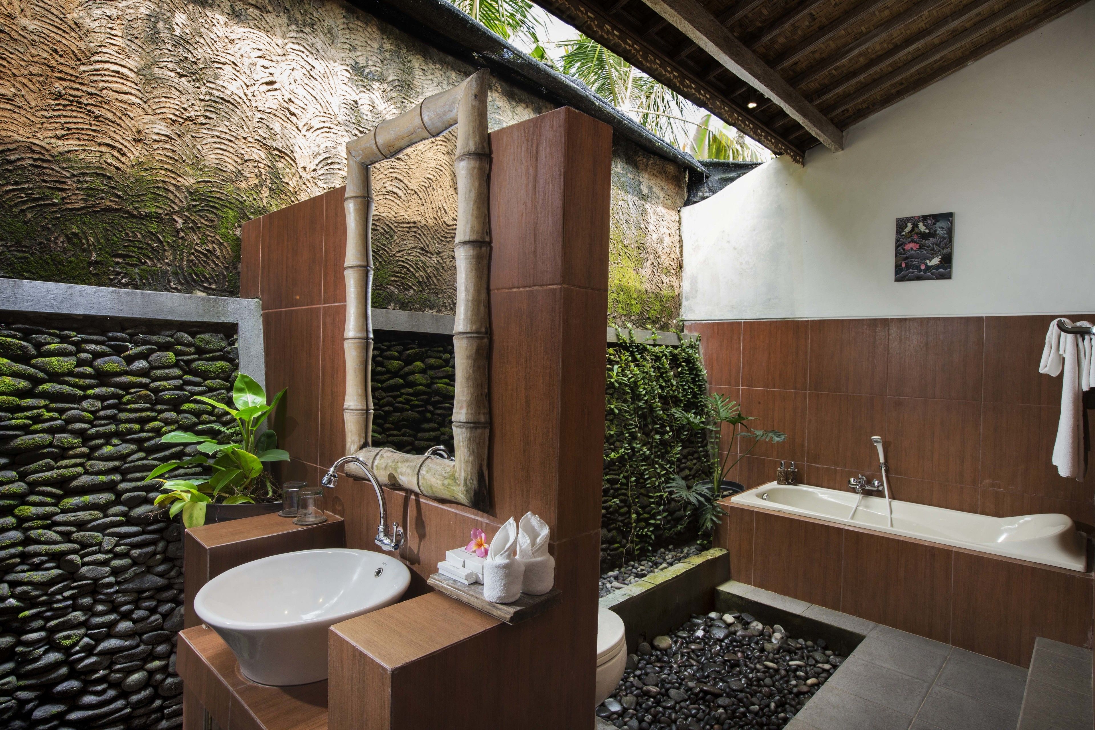 Un baño moderno con pared de piedra, tocador de madera, lavamanos grande y bañera.