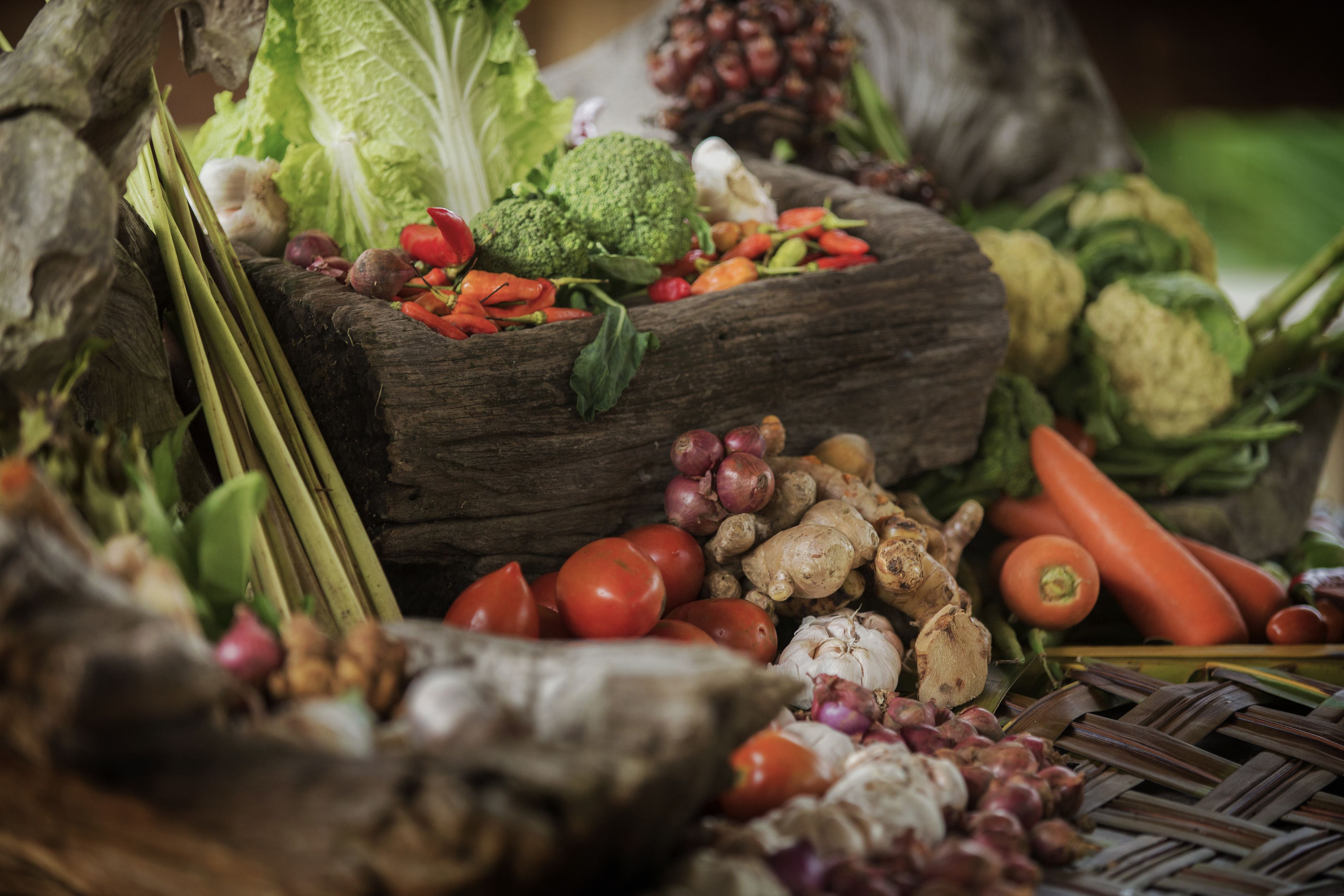 A variety of fresh vegetables displayed on a rustic wooden surface.