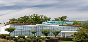 A modern building with a glass facade, a rooftop garden, and a mural. - Boticas Hotel Art & Spa (Boticas)