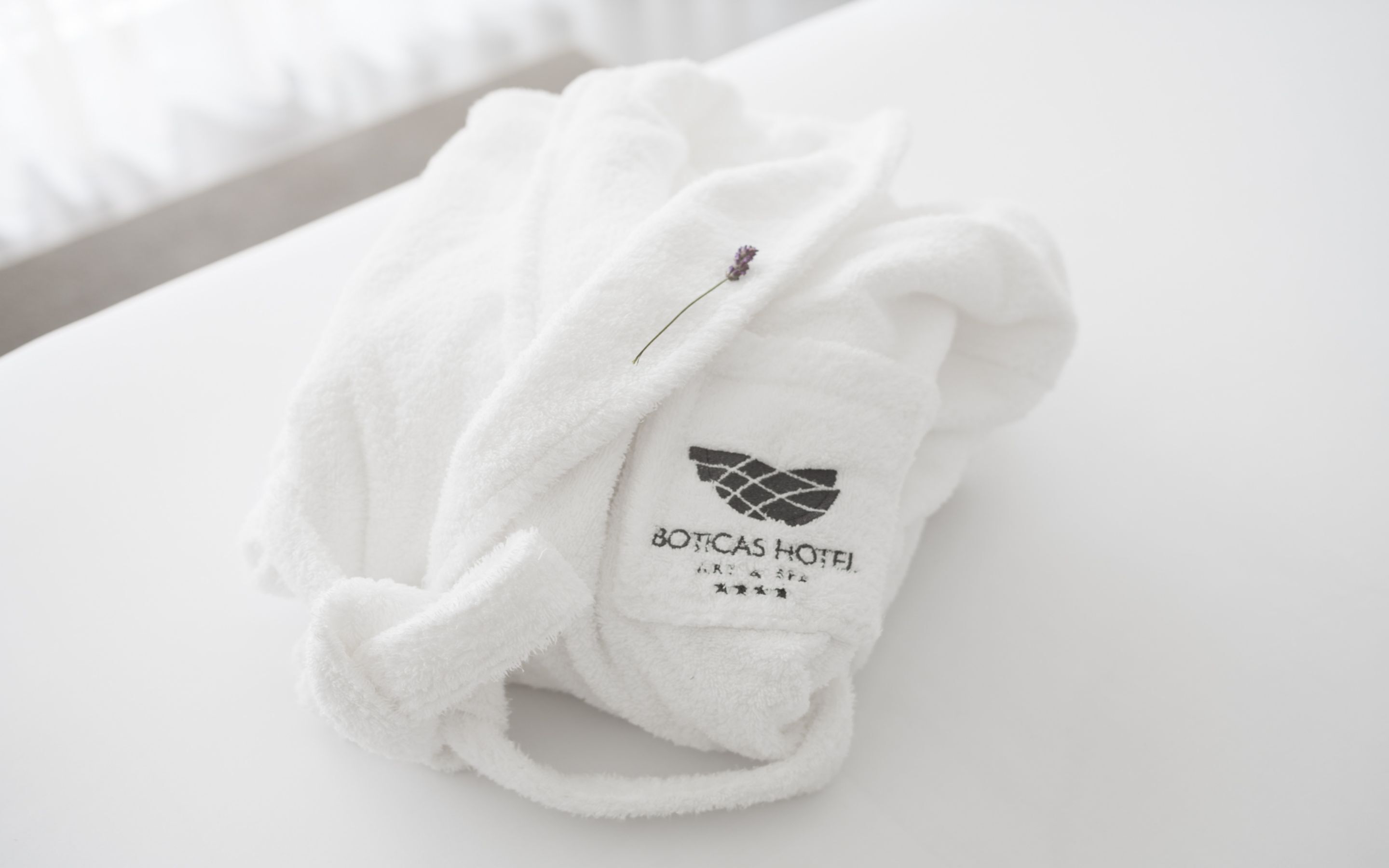 Toalla blanca con un logotipo y texto que indica que pertenece al Hotel Boticas.