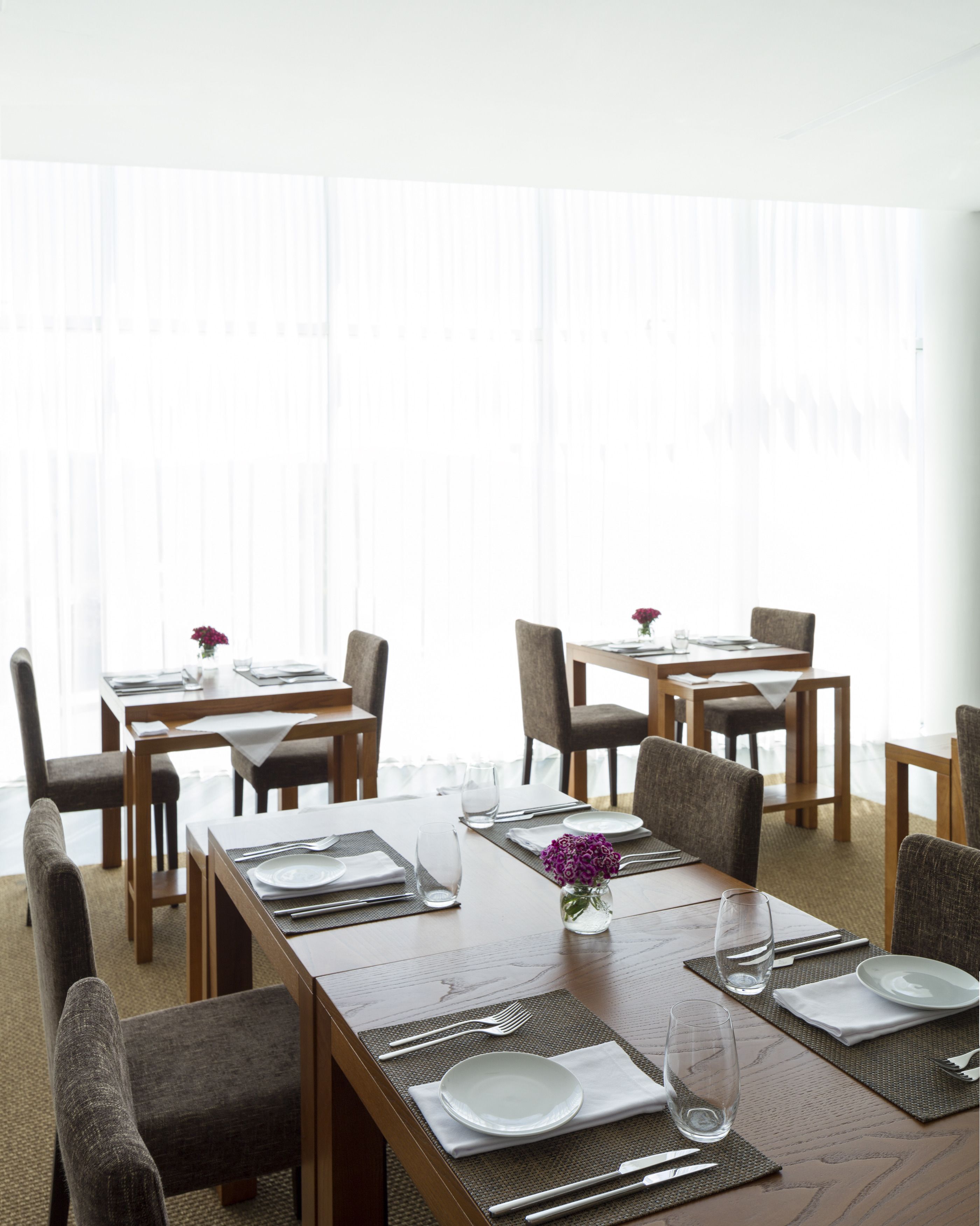 Area pranzo con tavoli e sedie in legno, predisposta per il servizio.