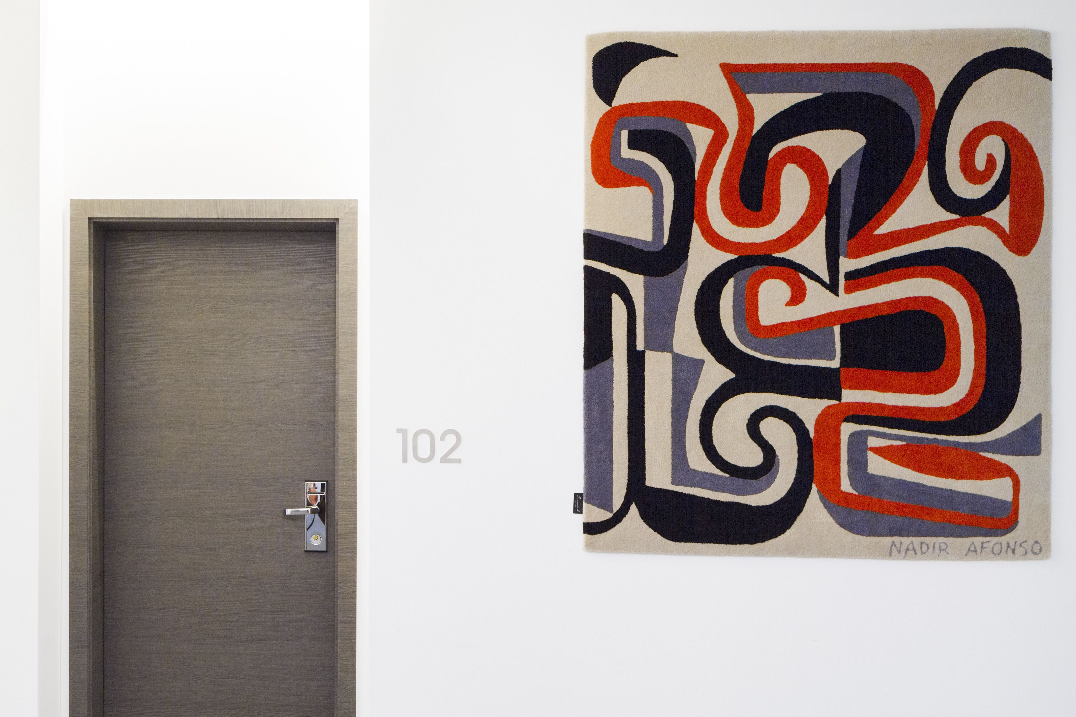 Una puerta con cerradura y una pared con un cuadro abstracto lleno de color.