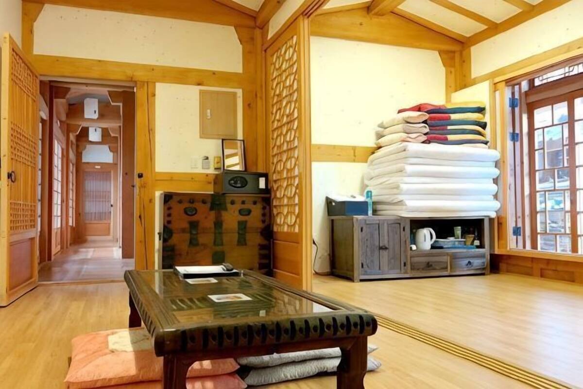 Um quarto japonês tradicional com tatames, uma mesa baixa e uma pilha de tecidos dobrados.