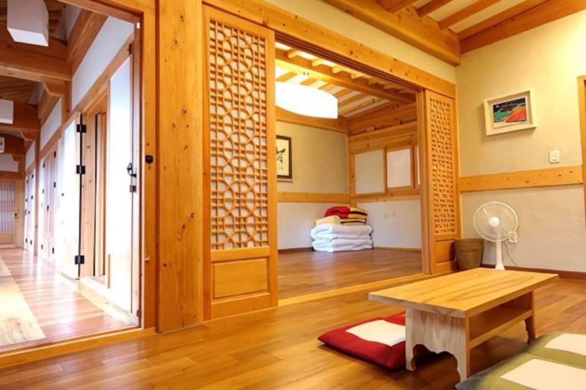 Ett traditionellt japanskt rum med tatamimattor på golvet, ett träbord, en fläkt och en skjutdörr.