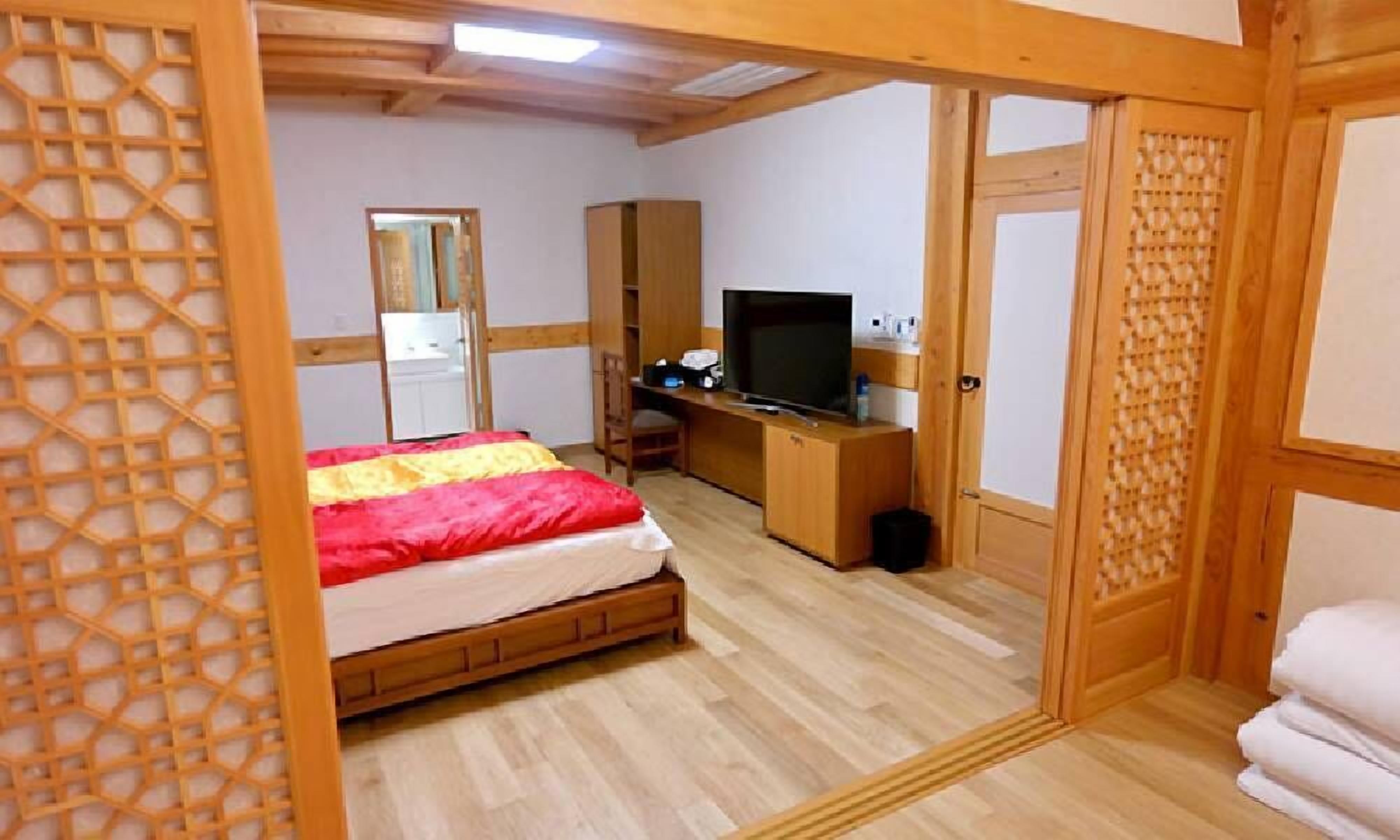 A room with a bed, a TV, a desk, and a wardrobe.