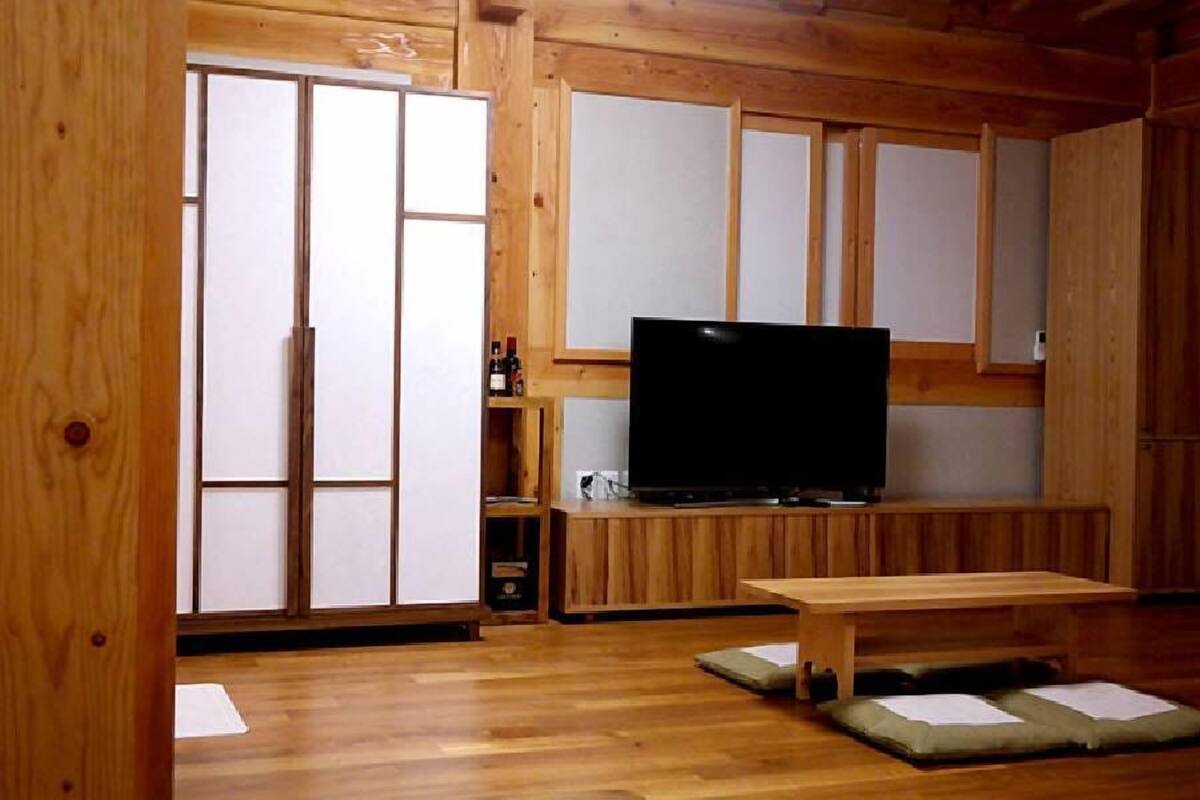 Quarto tradicional japonês com tatames, televisão e um banco de madeira.