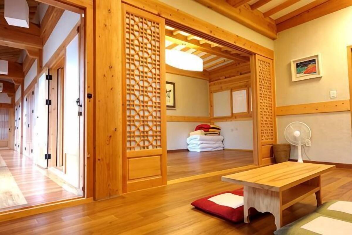 Um quarto tradicional japonês com tatames, uma mesa de madeira, um leque e uma porta deslizante.